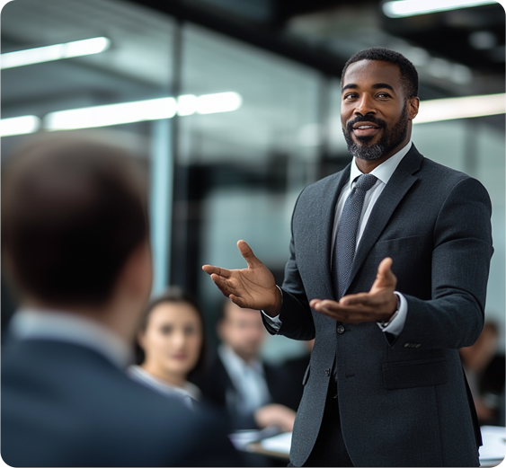 A man in a suit speaks to several other suited individuals in a conference room.